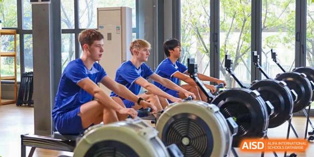 A close-up shot of several Wycombe Abbey School Hangzhou students using indoor rowing machines in a fitness center.