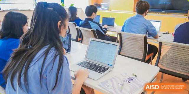 Students at Xi'an Liangjiatan International School collaborate on a project, looking at a laptop screen together in a classroom.