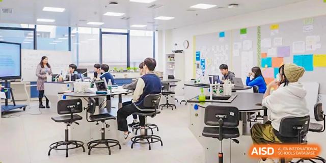 Students at Xi'an Liangjiatan International School work individually on laptops and at tables in a bright, modern learning space.