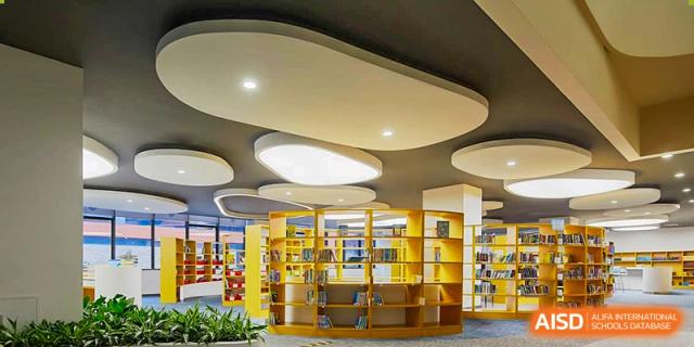 A bright, modern common area or library at Xi'an Liangjiatan International School with yellow shelving and circular lights on the ceiling.