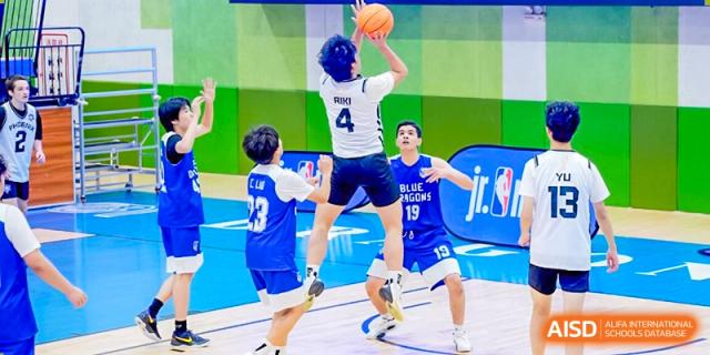 A player from Xi'an Liangjiatan International School wearing a blue and white jersey with the number 4 jumps high to take a shot over a defender during a competitive basketball game.