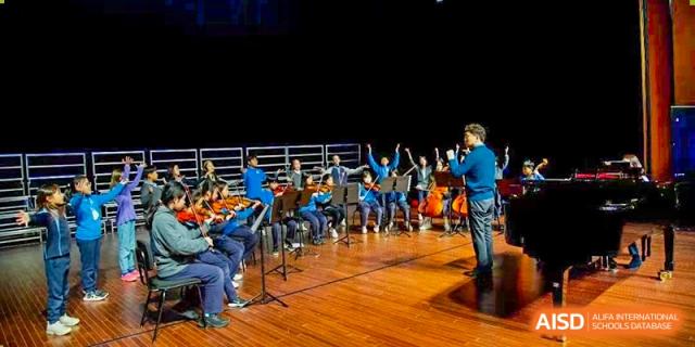 Xi'an Liangjiatan International School students perform a song or play instruments on an outdoor stage at night during a school festival.