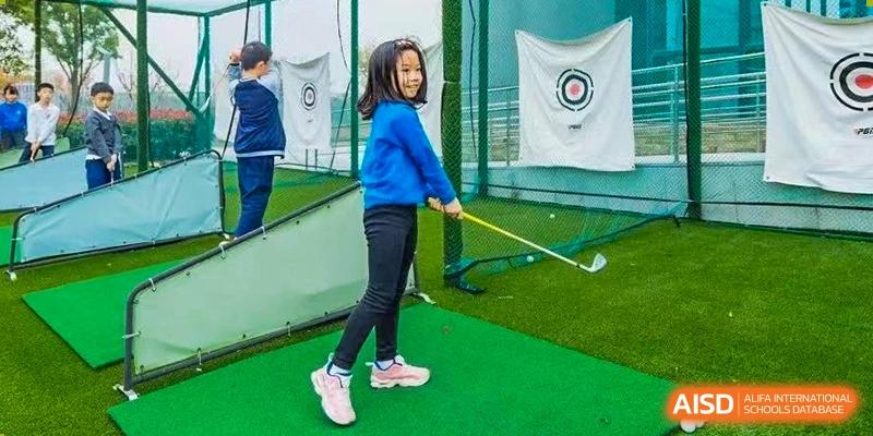 A young girl at Xi'an Liangjiatan International School practices her golf swing on a small patch of artificial turf.