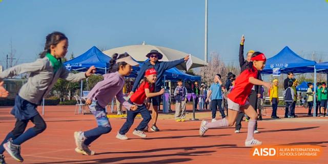 Xi'an Liangjiatan International School students participate in an outdoor sports day or athletic event on a field under a large tent structure.