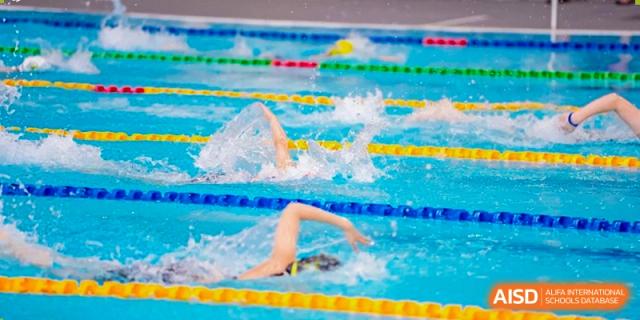 Close-up of a competitive swimmer from Xi'an Liangjiatan International School during a freestyle race, showing the splash and water turbulence.