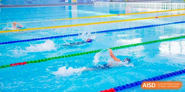 An underwater view of a swimmer from Xi'an Liangjiatan International School doing the freestyle stroke in a bright blue pool.