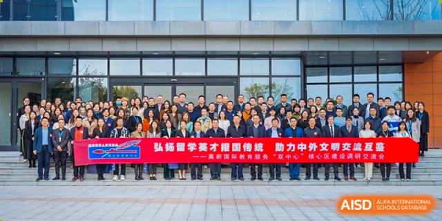 A large group photo of staff and faculty from Xi'an Liangjiatan International School standing outdoors in front of a red banner with Chinese text.