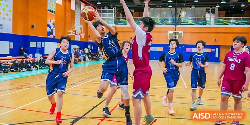 Xiamen International School students playing a spirited game of basketball indoors, with one student attempting a shot.