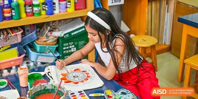 A female Xiamen International School student focused on painting a colorful mandala design in an art class.