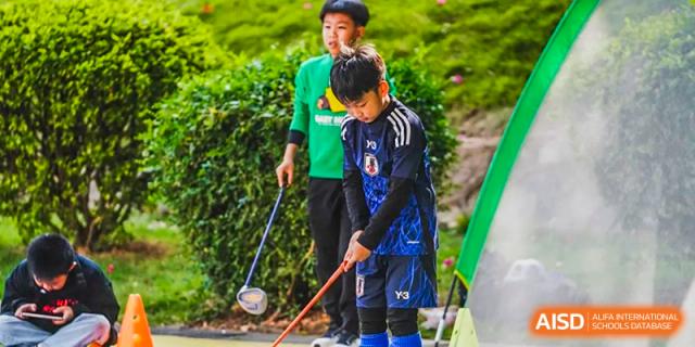 A young Xiamen International School student practicing golf or a similar sport on the field.