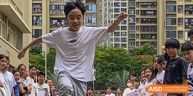 An Xiamen International School student participating in an outdoor sports event or run, with a crowd watching.