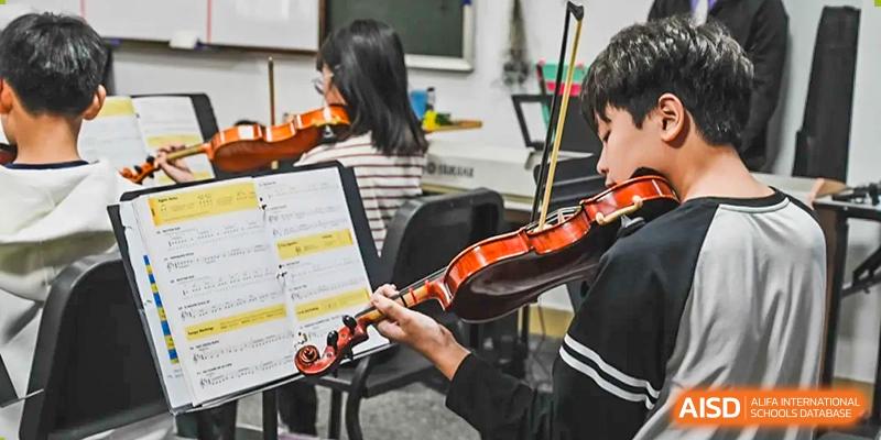 An Xiamen International School student playing the violin during a musical performance, with sheet music visible.