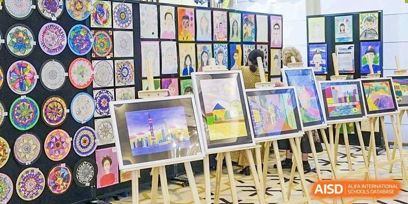An art exhibition at Xiamen International School displaying student paintings and drawings on easels.