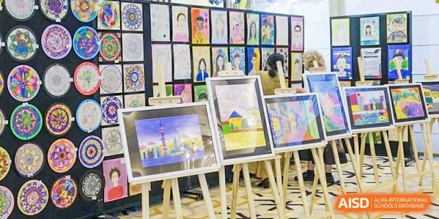 An art exhibition at Xiamen International School displaying student paintings and drawings on easels.