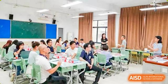 Yali High School International Department students and a teacher having a discussion or meeting around tables in a brightly lit classroom.