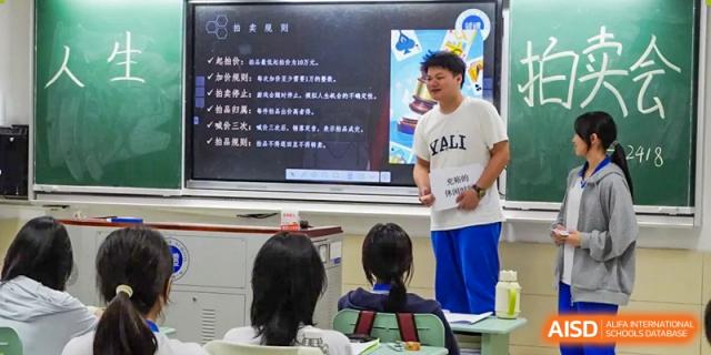 A Yali High School International Department male student giving a presentation in a classroom using a projector or interactive whiteboard.