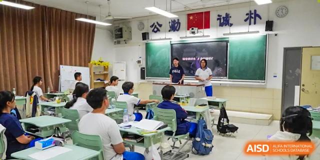 A teacher talking to Yali High School International Department students seated at desks in a classroom.
