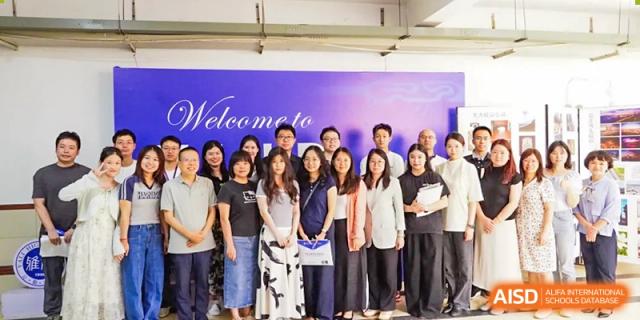 A group of Yali High School International Department staff or students posing for a photo in front of a welcome banner at an event.