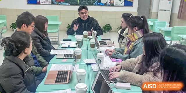 A small group of Yali High School International Department teachers or staff having a discussion or working on laptops around a table.