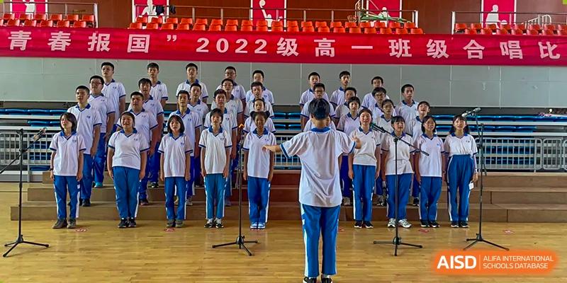 Yali High School International Department students performing in a choir or group assembly on stage.