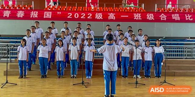 Yali High School International Department students performing in a choir or group assembly on stage.