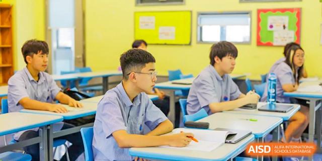 A male student at Yew Chung International School of Qingdao seated at a desk, paying close attention during a class lesson.