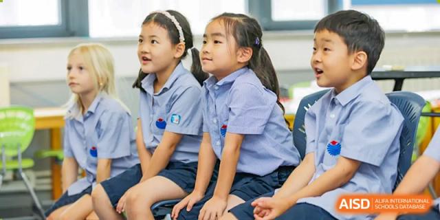 Two young female students at Yew Chung International School of Qingdao seated side-by-side, wearing their school uniforms.