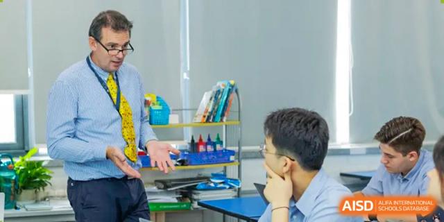 A teacher at Yew Chung International School of Qingdao having a focused discussion with a male student in a classroom setting.