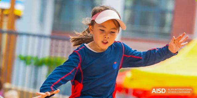 A young female student at Yew Chung International School of Qingdao wearing a visor and concentrating during an outdoor sports activity.