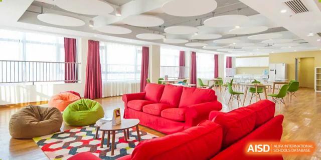An interior view of a vibrant common area or lounge at Yew Chung International School of Qingdao with comfortable red couches.
