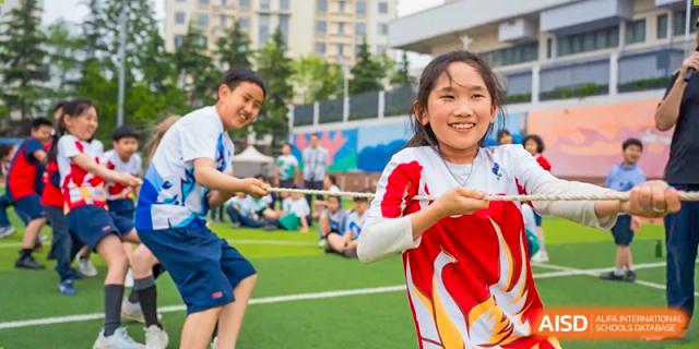 A female student at Yew Chung International School of Qingdao enthusiastically participating in an outdoor tug-of-war competition.