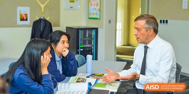 A teacher from Yew Wah International Education School of Zhejiang Tongxiang interacting with a student in a classroom setting.