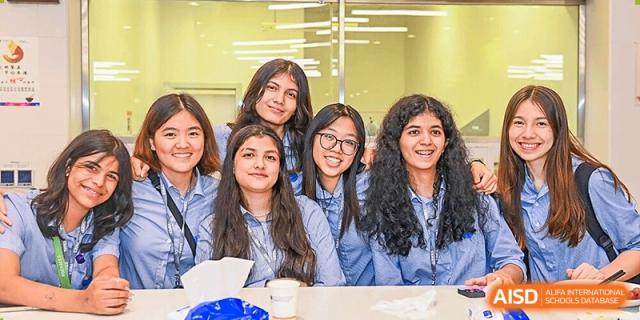 Group of smiling female students from Yew Wah International Education School of Zhejiang Tongxiang posing together in a classroom.
