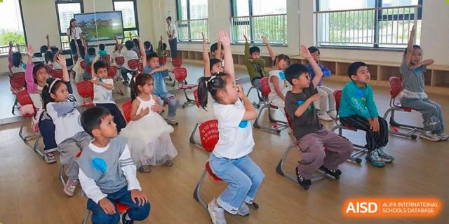 Young children from Yew Wah International Education School of Zhejiang Tongxiang participating in a lively indoor activity or dance class.