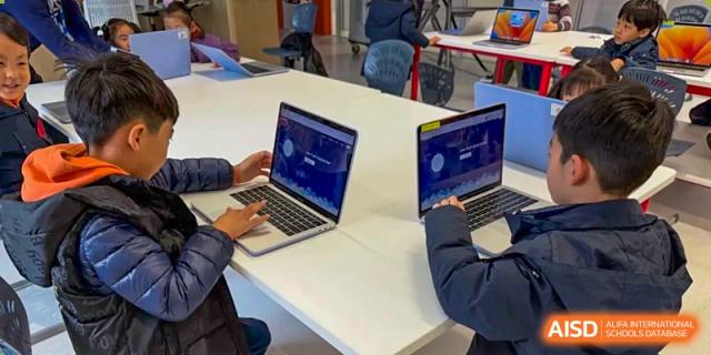 Students from Yew Wah International Education School of Zhejiang Tongxiang working together on laptops at a table.