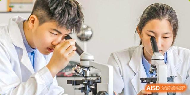 Student at Yew Wah International Education School of Zhejiang Tongxiang using a microscope in a science lab.
