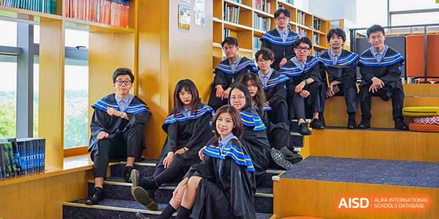 Group of students from Yew Wah International Education School of Zhejiang Tongxiang sitting among bookshelves in the school library.