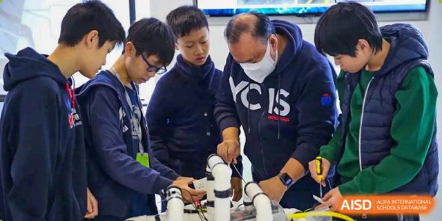 Teacher and students at Yew Wah International Education School of Zhejiang Tongxiang working together on a robotics or science project.