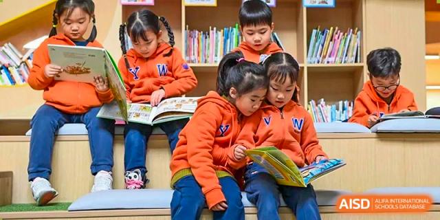 Young children from Yew Wah International Education School of Zhejiang Tongxiang reading a book together in the library.