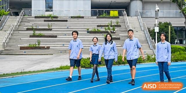 Four students from Yew Wah International Education School of Zhejiang Tongxiang in blue and white school uniforms walking on a blue running track.