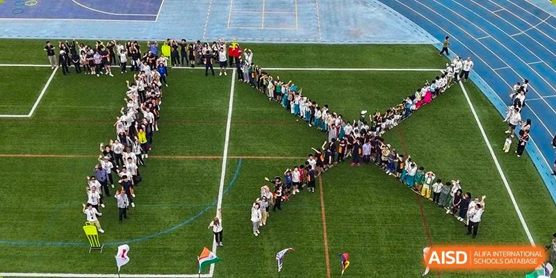 A large group of students and faculty from Yew Wah International Education School of Zhejiang Tongxiang lined up on a green sports field.