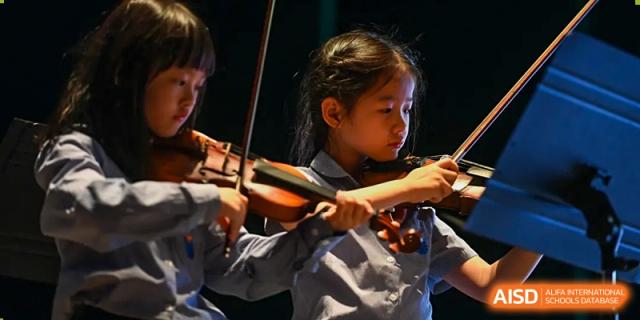 A young female student from Yew Wah International Education School of Zhejiang Tongxiang intently playing the violin.