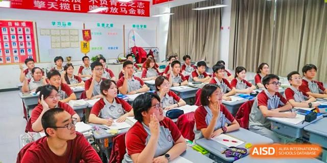 A large classroom of students in red uniforms attending a lecture or working at their desks at Zibo MacDuffie Bilingual High School.