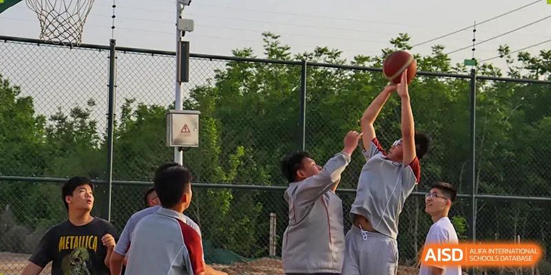 Student reaching for a high-five or a ball during an outdoor activity at Zibo MacDuffie Bilingual High School.