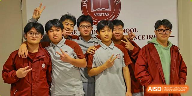 A group of male students posing together indoors, smiling at Zibo MacDuffie Bilingual High School.