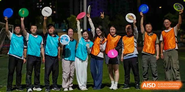 A small group of students celebrating or posing with frisbees during a night activity at Zibo MacDuffie Bilingual High School.