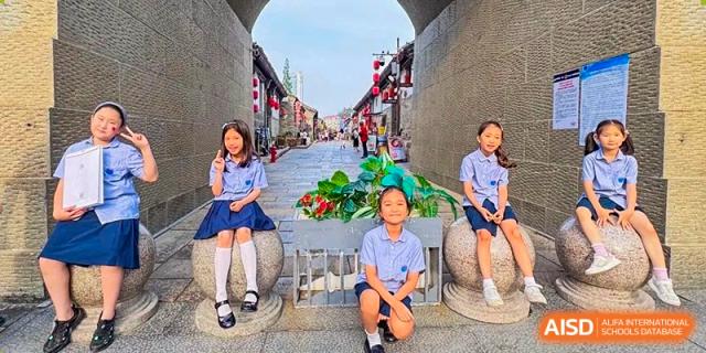 Yew Wah International Education School of Yantai Campus students sitting outdoors with flowers during a school trip or cultural visit.