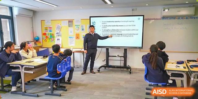 A teacher at Yew Wah International Education School of Yantai Campus pointing to a presentation on a large digital screen during a class.