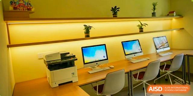 A well-lit area with Apple iMac computers and desks, possibly a study or computer lab at Yew Wah International Education School of Yantai Campus.