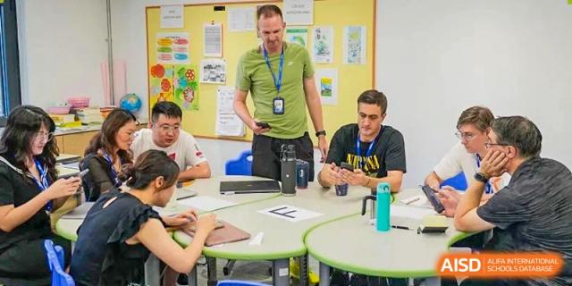 An engaging group discussion with a teacher and students seated at a round table at Yew Wah International Education School of Yantai Campus.